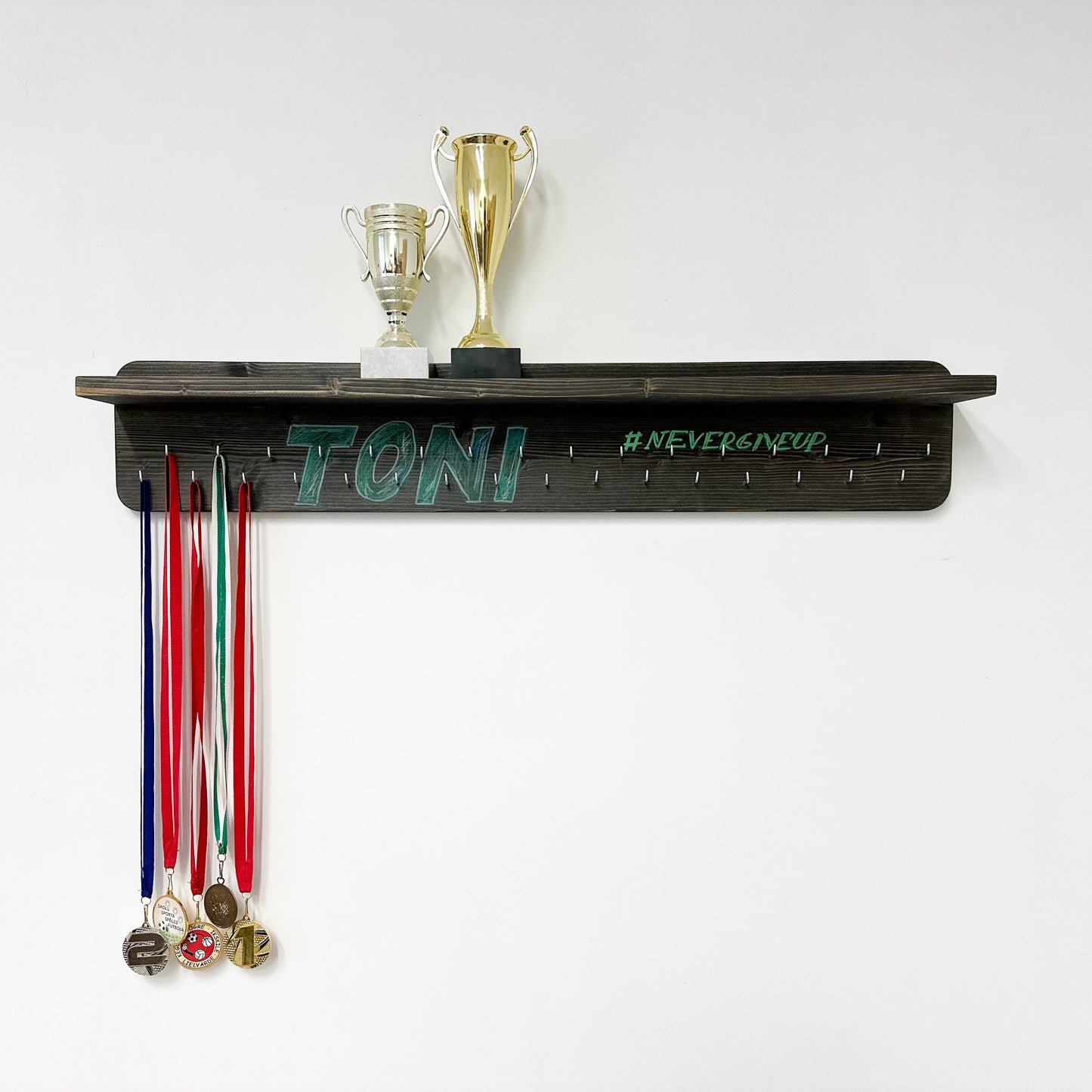 Pie sienas stiprināms medaļu turētājs ar trofeju plauktu un personalizētiem āķiem