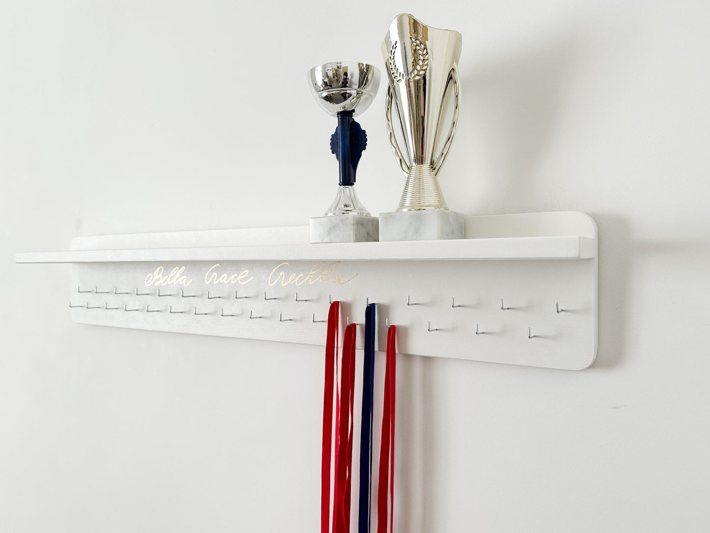 Pie sienas stiprināms medaļu turētājs ar trofeju plauktu un personalizētiem āķiem