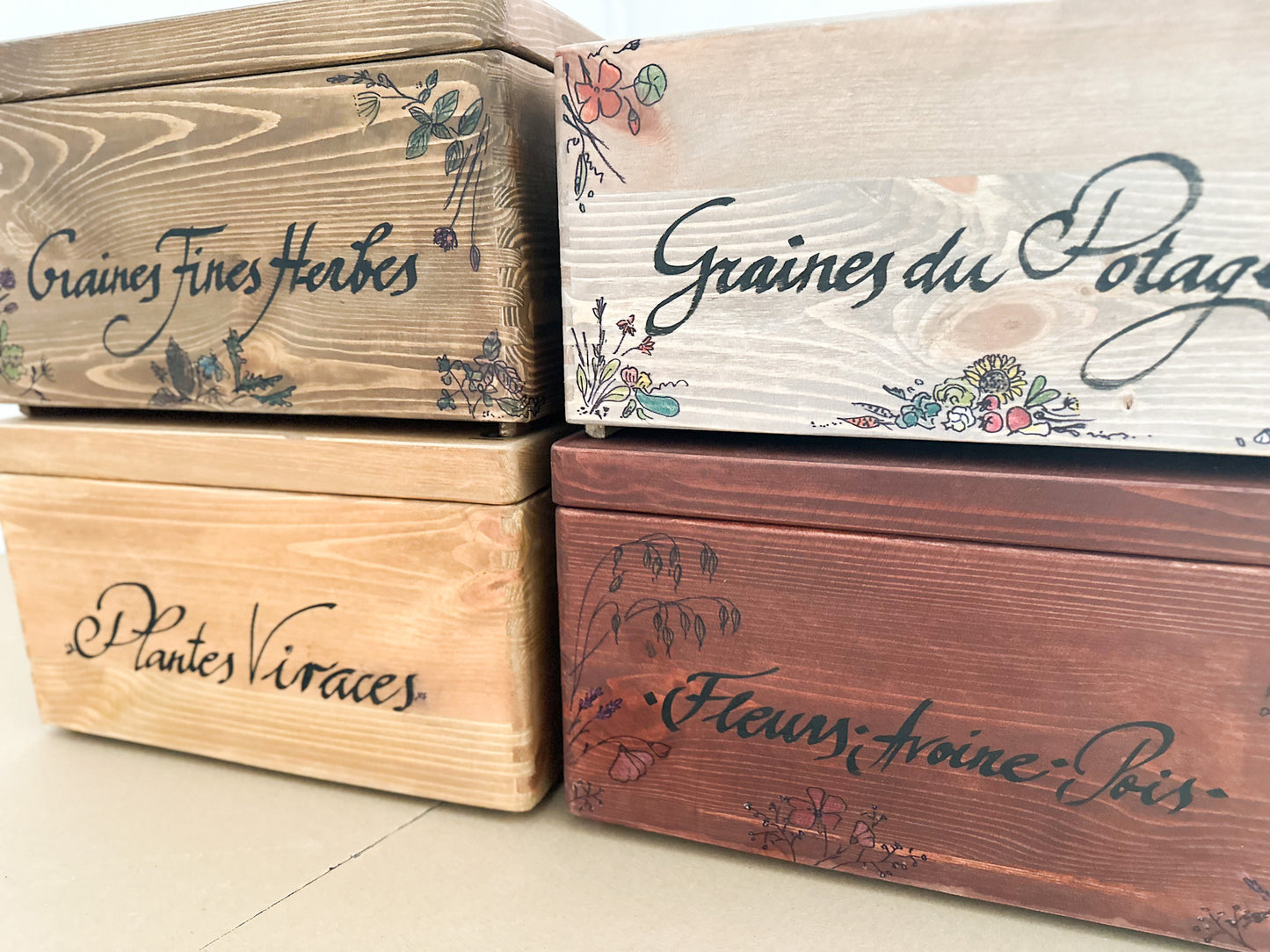 Wooden boxes with handmade text and floral designs on a light background
