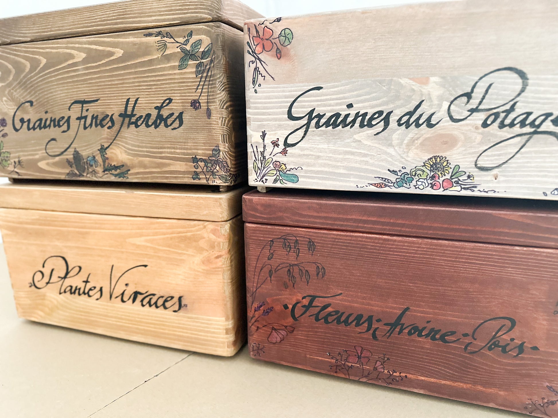 Wooden boxes with handmade text and floral designs on a light background